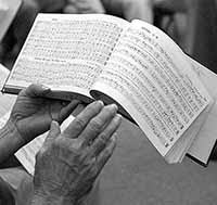 Hands hold a hymn book.