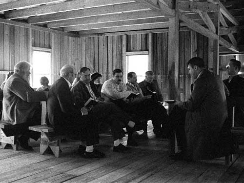 Members congregate inside a primitive wood chruch