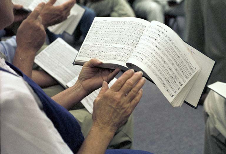 Hands holding a shape-note hymn book.