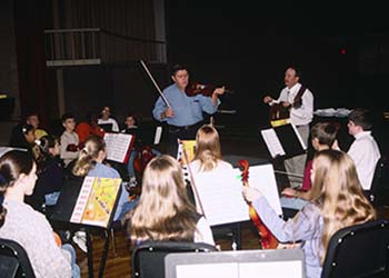 Henry Rutland and Paul Massey teach the fiddle to a young class.
