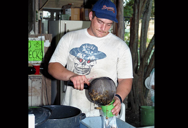 A young man pours boiled peanuts in a bag.