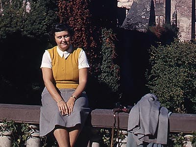 Leona sitting on a rail in unidentified location, 1950's.